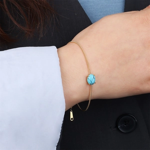 Detailed shot of 18k gold chain bracelet with oval turquoise stone on model wrist