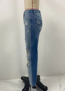 Dettaglio dei jeans strappati con design patchwork bicolore blu e rifiniture sfrangiate