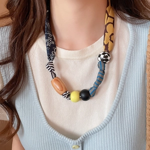 Détail du collier cœur avec cordon en tissu floral et perles mixtes en bois et résine