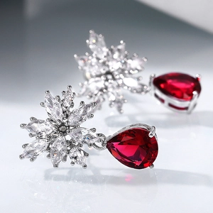 Macro view of silver teardrop red zircon earrings with detailed snowflake zircon stud