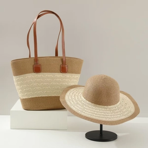 Detail of straw tote bag and sun hat set featuring camel and beige woven textures