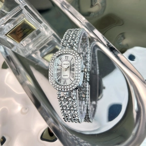 Macro view of silver luxury rhinestone-encrusted oval quartz watch on a reflective surface