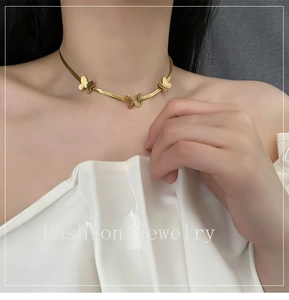 Gros plan d'un collier ras du cou papillon doré avec trois petits breloques papillons