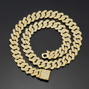 Detail of 14mm gold Cuban link chain with sparkling white rhinestones on black background