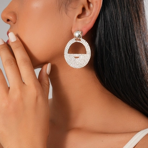 Close-up of a large silver geometric round earring with white crystals on a model