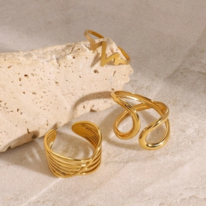 Detailed view of three gold-plated stainless steel rings on a minimalist stone background