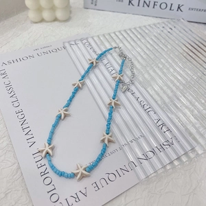 Detail of blue beaded necklace with white starfish charms and silver lobster clasp