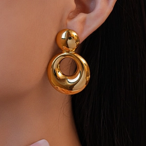 Gros plan de boucles d'oreilles rondes en acier inoxydable plaqué or 18k sur un mannequin