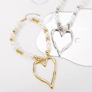 Macro view of gold and silver hollow heart pendants on elegant pearl bead necklaces