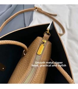 Detail of premium brown pebble leather tote showing high-gloss gold zipper and inner pocket