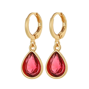 Detailed view of gold huggie earrings with faceted red teardrop gemstone charms