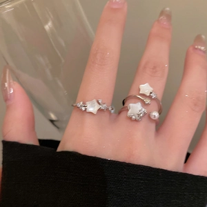 Detail shot of open silver star rings with mother of pearl and pearls on a finger