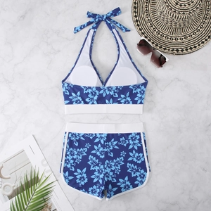 Flat lay detail of floral halter bikini set with swim shorts on marble background