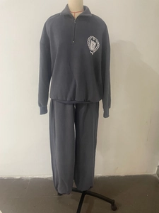 Détail de l'emblème collégial sur l'ensemble sweat-shirt à demi-zip et jogging gris foncé