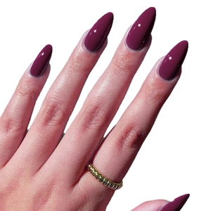 Glossy deep berry long stiletto press-on nails with shiny finish on white background