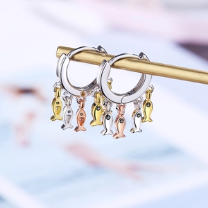Macro shot of silver, gold, and rose gold fish charm earrings with black zircon eyes