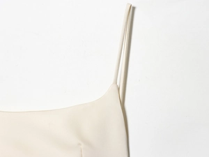 Detail of thin shoulder strap and cream satin fabric on a women's summer dress