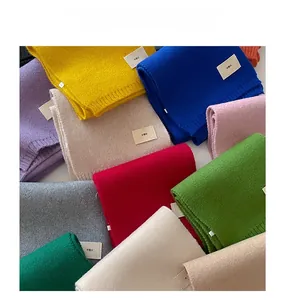 Flat lay display of colorful knitted scarves with emo fabric labels in various solid tones
