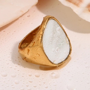 Makroaufnahme von 18K vergoldetem Ring mit weißem Tropfen-Inlay und Wassertropfen