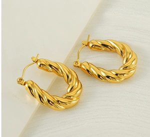 Macro shot of gold twisted U-shape hoop earrings with polished metal texture and clasp