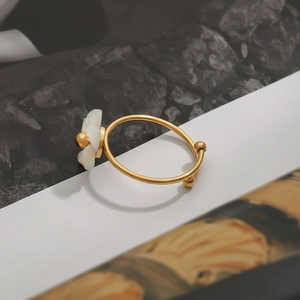 Close-up of golden stainless steel ring with white flower and adjustable bead detail
