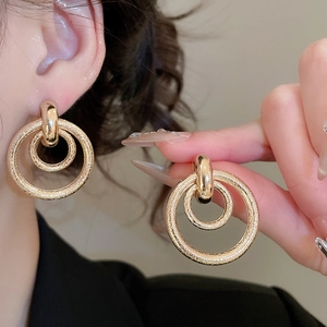 Détails de boucles d'oreilles dorées à double cercle avec motifs martelés et lisses