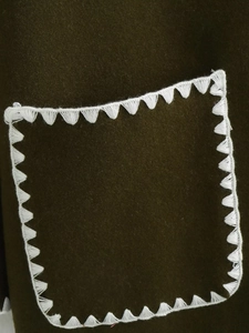 Detail view of deep green wool coat featuring a pocket with white triangle stitching
