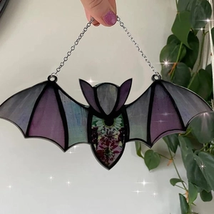 Detail of bat pendant with purple stained glass wings and embossed floral patterns