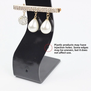 Detail of gold brooch with pavé rhinestones and hanging white teardrop pearls on a display