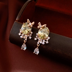 Macro view of gold 18k butterfly earrings with yellow stone and pearl detail