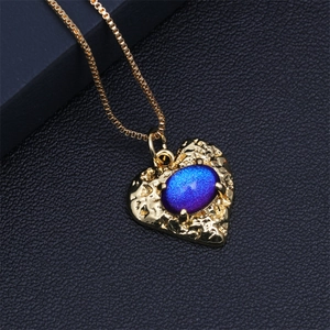 Close-up of golden heart pendant with hammer texture and blue-purple stone on leather