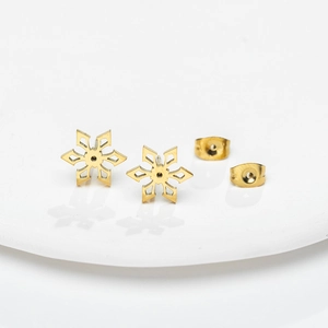 Minimalist gold snowflake stud earrings in stainless steel on white ceramic base