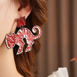 Close-up of a red enamel crown cat earring with silver trim worn by a model