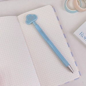 Close-up of a blue cloud retractable gel pen featuring a smiling cloud clip on grid paper