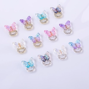 Macro detail of gradient resin butterfly nail charms with sparkling rhinestone base