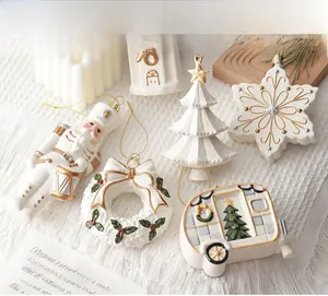 Detailed view of white ceramic Christmas ornaments with gold accents and hanging strings