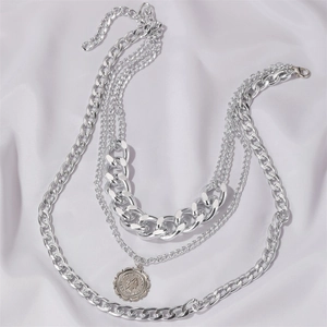 Detailed view of silver multi-layered necklace with coin pendant on silk background