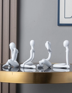 Detailed view of four white abstract sculptures in various poses on a golden table