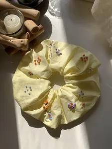 Dettaglio di scrunchie giallo chiaro fatto a mano con perline colorate su tessuto premium