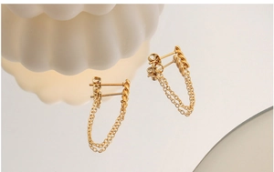 Detail of gold-plated double-layer tassel chain earrings reflecting on a mirror