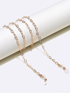 Detail view of heart-shaped gold eyewear chain wrapped on minimalist display stand