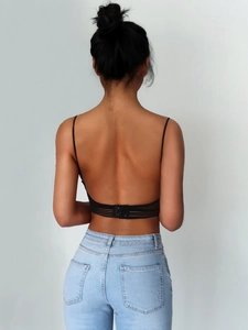 Detail of black backless bra with thin straps and sheer mesh trim on model's back