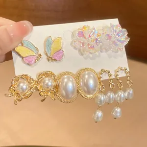 Detail of four-piece earring set featuring butterfly, flower, and pearl studs on white card