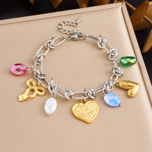 Macro shot of colorful crystal heart pendants and golden bow charms on chunky chain link