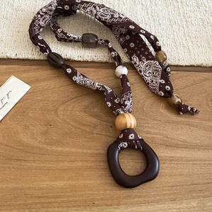 Detailed close-up of Bohemian necklace with paisley fabric, wooden beads and ring pendant