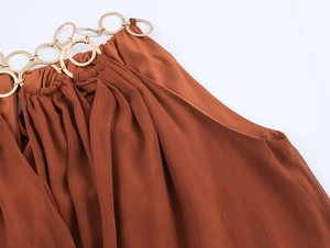 Detail des Metallring-Neckholders und plissierter Chiffon-Stoff in Karamellfarbe