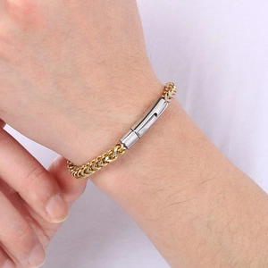 Close-up of gold and silver wheat chain bracelet with a cylindrical clasp on a wrist