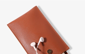 Close-up of brown leather phone pouch showing magnetic buckle and premium texture