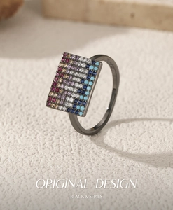 Macro detail of a pixel-style rectangular ring with colorful pavé stones on black metal