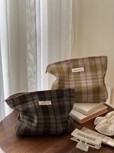 Detailed close-up of vintage plaid wool makeup bags in brown and tan on wooden table
